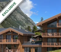 Wooden alpine lodges in a mountainous landscape under a blue sky with "Exclusive" label in the top left corner.